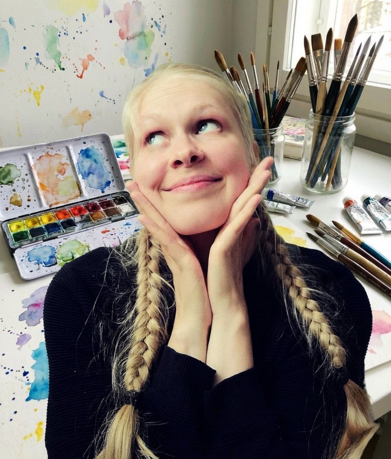 Jasu, the artist behind Jasu Wonder World, at her painting table with watercolors and brushes